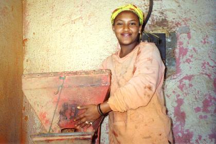 Girl grinding spices (berbere) in a Medeber workshop.