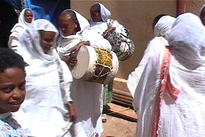 Woman dancing and beating the drums in front of the party tent.