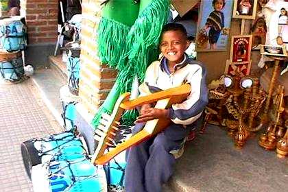 Covered market in Asmara - boy playing a traditional Eritrean instrument.