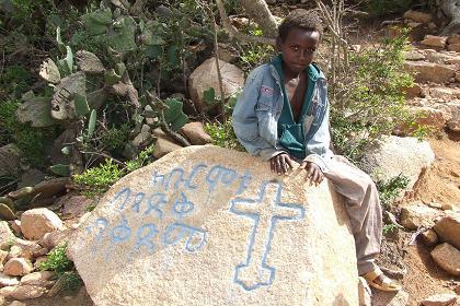 Filmon one of my guides on a landmark indicating the end of the hike: one kilometer from Debre Bizen Monastery.